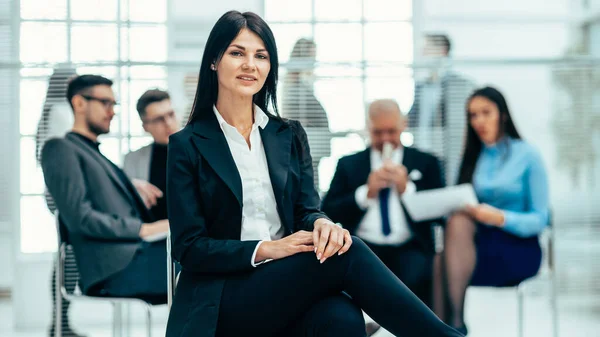 Zelfverzekerde jonge zakenvrouw zittend in een modern kantoor — Stockfoto