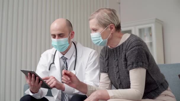 Doctor en casa con una tableta digital hablando con su paciente. — Vídeo de stock