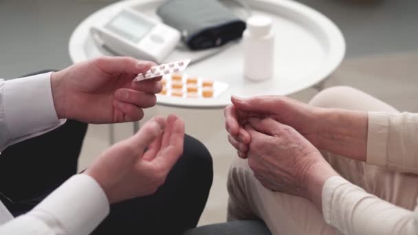 Médico le receta medicamentos a su paciente durante una visita domiciliaria. — Vídeos de Stock