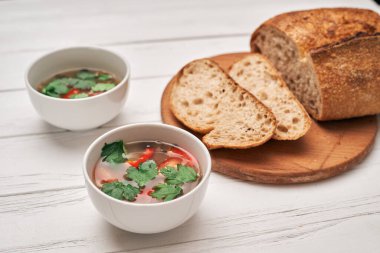 Tahta zemin üzerinde kepekli ekmek ve bir kase çorba..