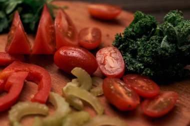 Tahta bir mutfak tahtasında dilimlenmiş turşu ve domates..