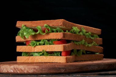 Yakın plan. Siyah arka planda lezzetli domatesli sandviç..