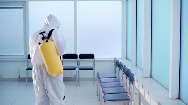 Opdrachtnemer in veiligheidsuniform desinfecterend kantoor dat covid-19-virus doodt — Stockvideo