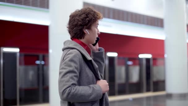 Жінка говорить на своєму смартфоні, стоячи на станції метро . — стокове відео