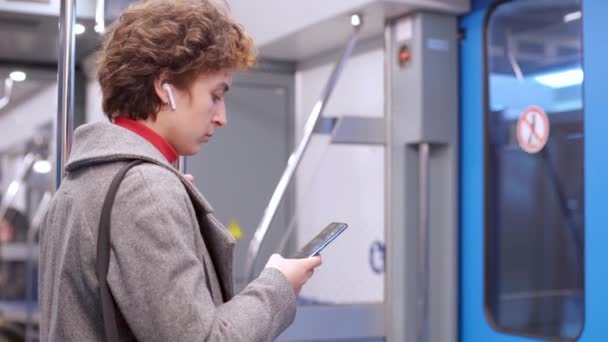 Jovem com um smartphone saindo de um carro de metrô. — Vídeo de Stock