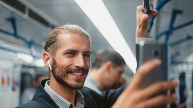 Metroda akıllı telefonunu kullanan çekici bir adam. .