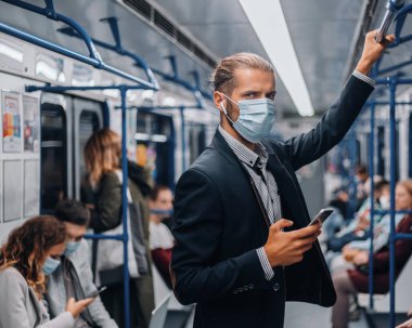 Bir metro vagonunda duran koruyucu maskeli yolcu..