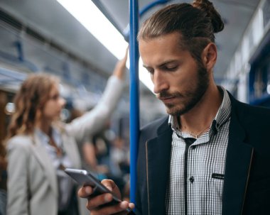 Genç adam akıllı telefonunu metroda kullanıyor..
