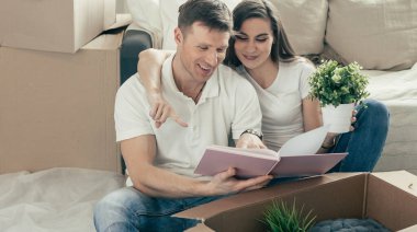 Yeni bir dairede oturan çift yerde aile fotoğraflarına bakıyor..