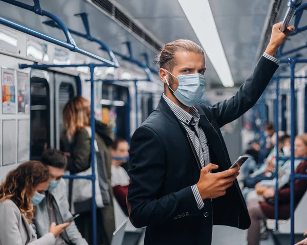 Passageiro em uma máscara protetora de pé em um carro de metrô. — Fotografia de Stock