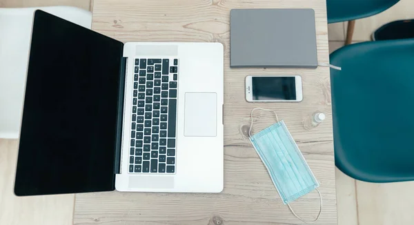 Laptop, Smartphone und Schutzmaske am Schreibtisch — Stockfoto