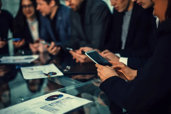 Funcionários usando seus smartphones para trabalhar com dados financeiros. — Fotografia de Stock