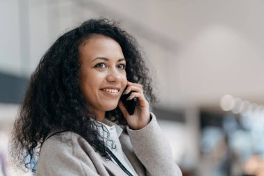 Bir alışveriş merkezinin kafeteryasında akıllı telefondan konuşan genç bir kadın. .