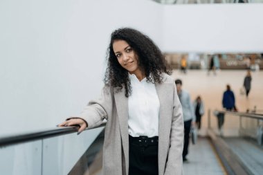 Alışveriş merkezinde yürüyen merdivende duran genç bir kadın..