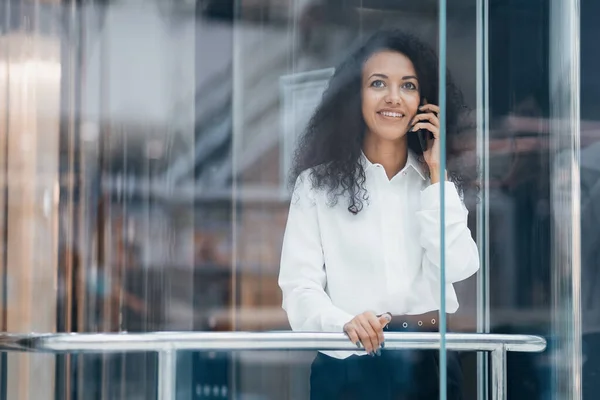 Mujer joven hablando en su teléfono inteligente mientras está de pie en el ascensor. — Foto de Stock