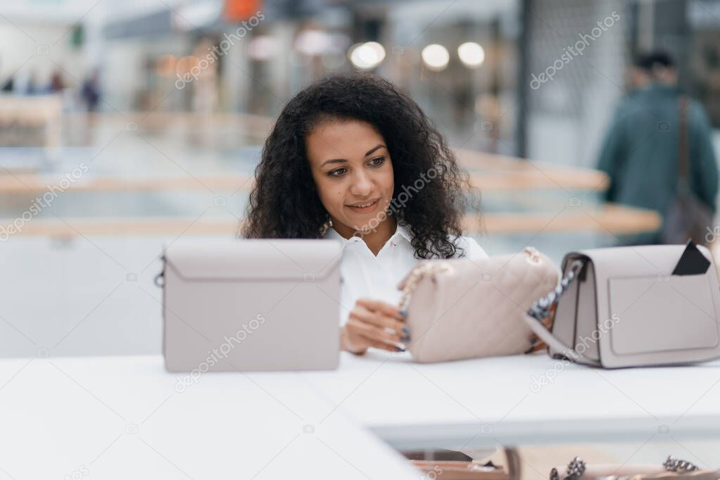 young woman looking at a handbag on the counter of a store.
