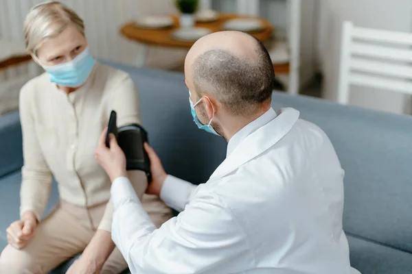 Médico en casa está midiendo la presión de su paciente. —  Fotos de Stock