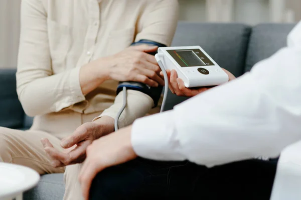 Hemläkare som mäter blodtrycket under ett besök hos patienten. — Stockfoto