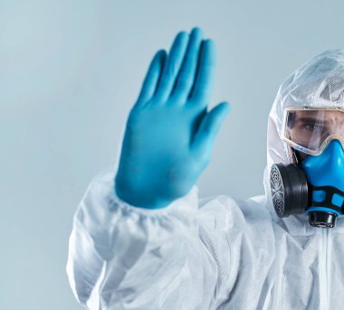 Biyolojik tehlike kıyafetli adam dur işareti yapıyor..