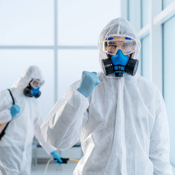 image of a confident disinfector standing in an office lobby .