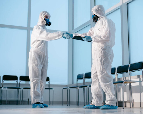 lab technicians in protective suits shaking hands.