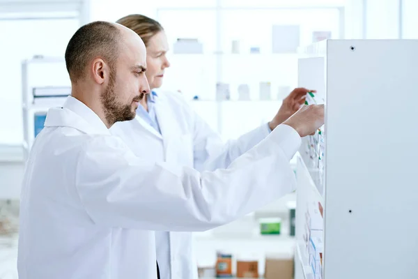 Hombre y una mujer farmacéuticos discutiendo medicamentos. — Foto de Stock