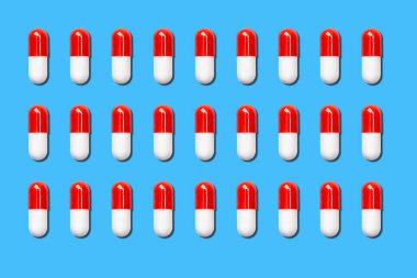 Mavi arka planda bir sürü kırmızı ve beyaz tıbbi kapsül var..