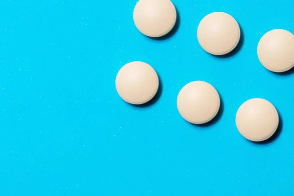 Round white tablets on a blue table . — Stock Photo, Image