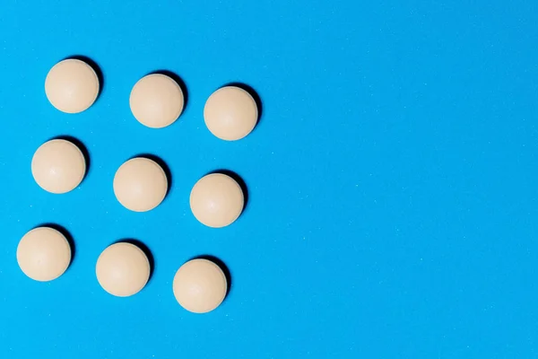 Veel ronde witte pillen op een blauwe tafel . — Stockfoto