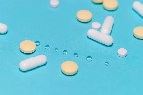 Seringa e várias pílulas em um fundo azul. — Fotografia de Stock