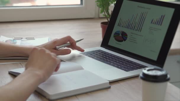 Doe dicht. zakenman met behulp van laptop en het maken van notities in Notepad. — Stockvideo