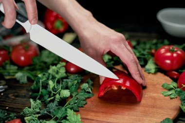 Adam tahta kesme tahtasıyla kırmızı biber dilimliyor..