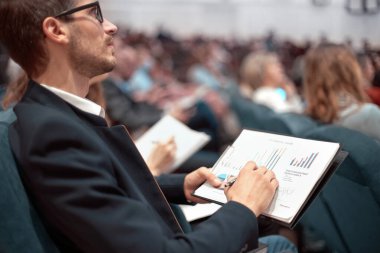 Ekonomik programı olan iş arkadaşları konferans salonunda oturuyorlar..
