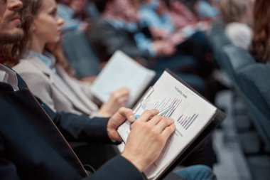 Yakın plan. Ekonomik programı olan bir iş adamı konferans salonunda oturuyor..