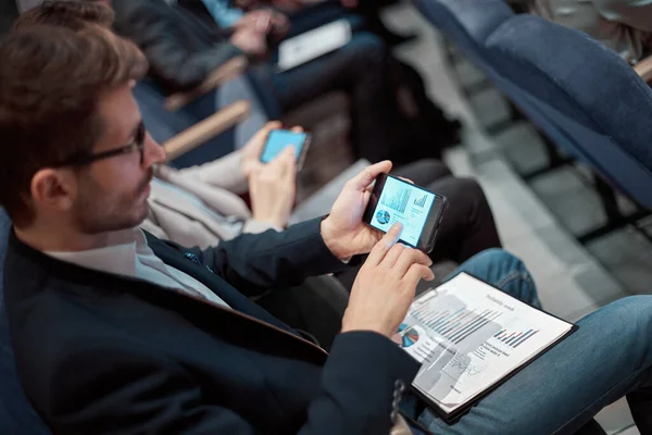 Homem de negócios usando seu smartphone enquanto sentado na sala de conferências. — Fotografia de Stock