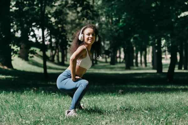 Smiling young woman does morning exercises in the park. — Stock Photo, Image