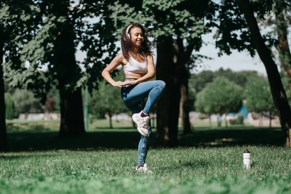 Glimlachende vrouw met koptelefoon uitvoeren van fitness-oefeningen in een — Stockfoto