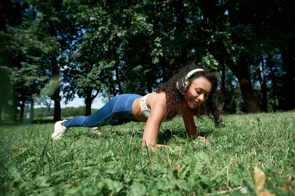 Jonge vrouw het uitvoeren van een plank oefening in het park. — Stockfoto