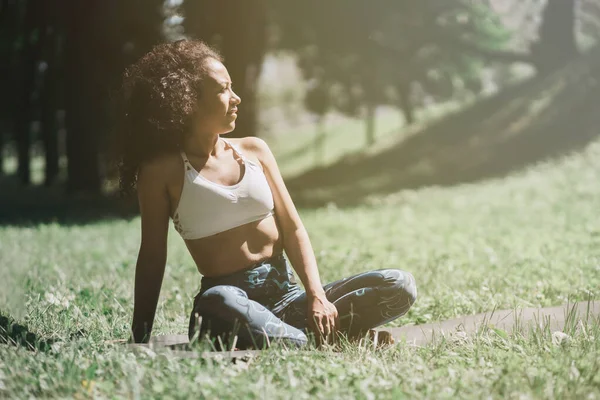Krásná žena sedí na trávě a relaxaci po cvičení — Stock fotografie