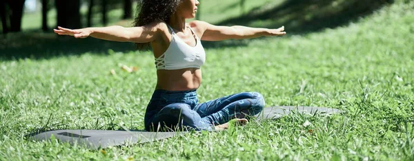 スポーティーな若い女性は草の上に座って瞑想します. — ストック写真
