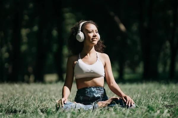 Mujer deportiva en auriculares relajantes a la música mientras se sienta o — Foto de Stock