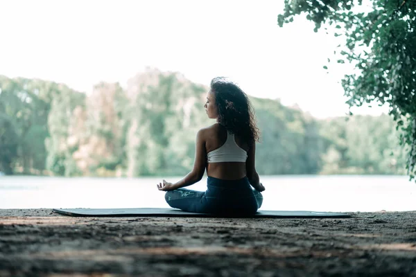 Jovem atlética meditando ao ar livre. vista traseira. — Fotografia de Stock