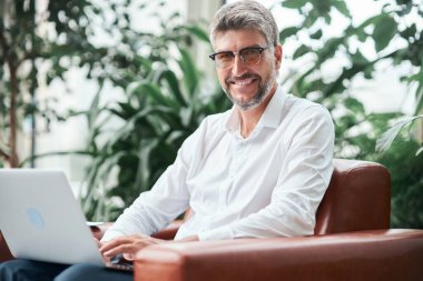 Bilgisayarlı bir iş adamı kameraya bakıyor. .