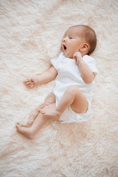 Geeuwen pasgeboren baby liggend op een zachte deken. — Stockfoto