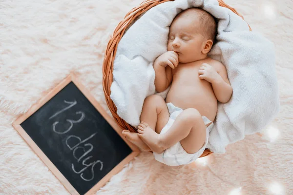 Schattig pasgeboren baby slaapt naast een schrijfbord . — Stockfoto