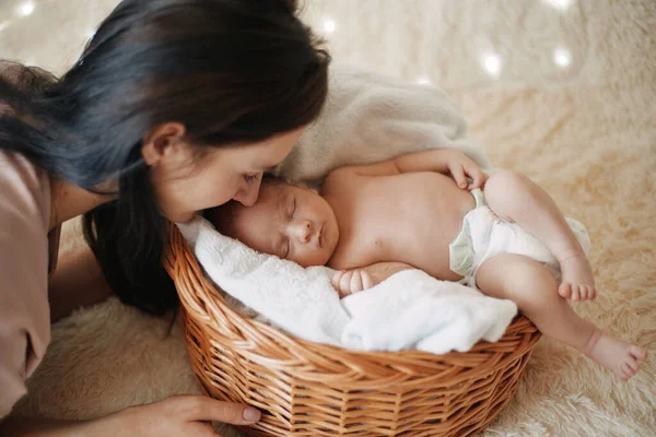 Mãe gentilmente olha para seu bebê recém-nascido adormecido. — Fotografia de Stock