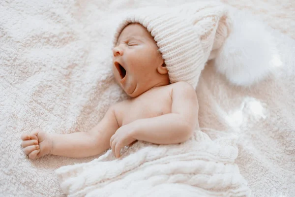 Schattig geeuwen pasgeboren baby in een witte gebreide hoed . — Stockfoto
