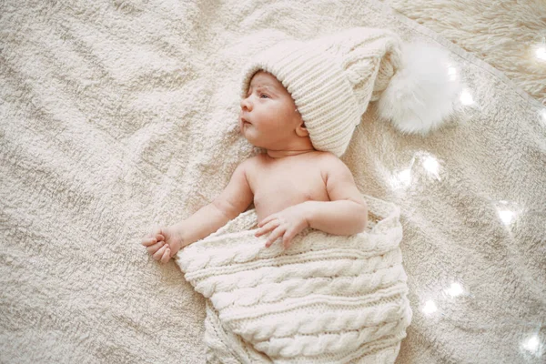 Cute newborn baby in a white knitted hat smiling in a dream . — Stock Photo, Image
