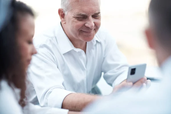 Smiling businessman looking at the screen of his smartphone . — Stock Photo, Image