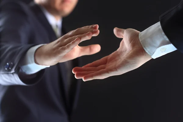 Photo of hands of business partners before handshake in black background — Stock Photo, Image